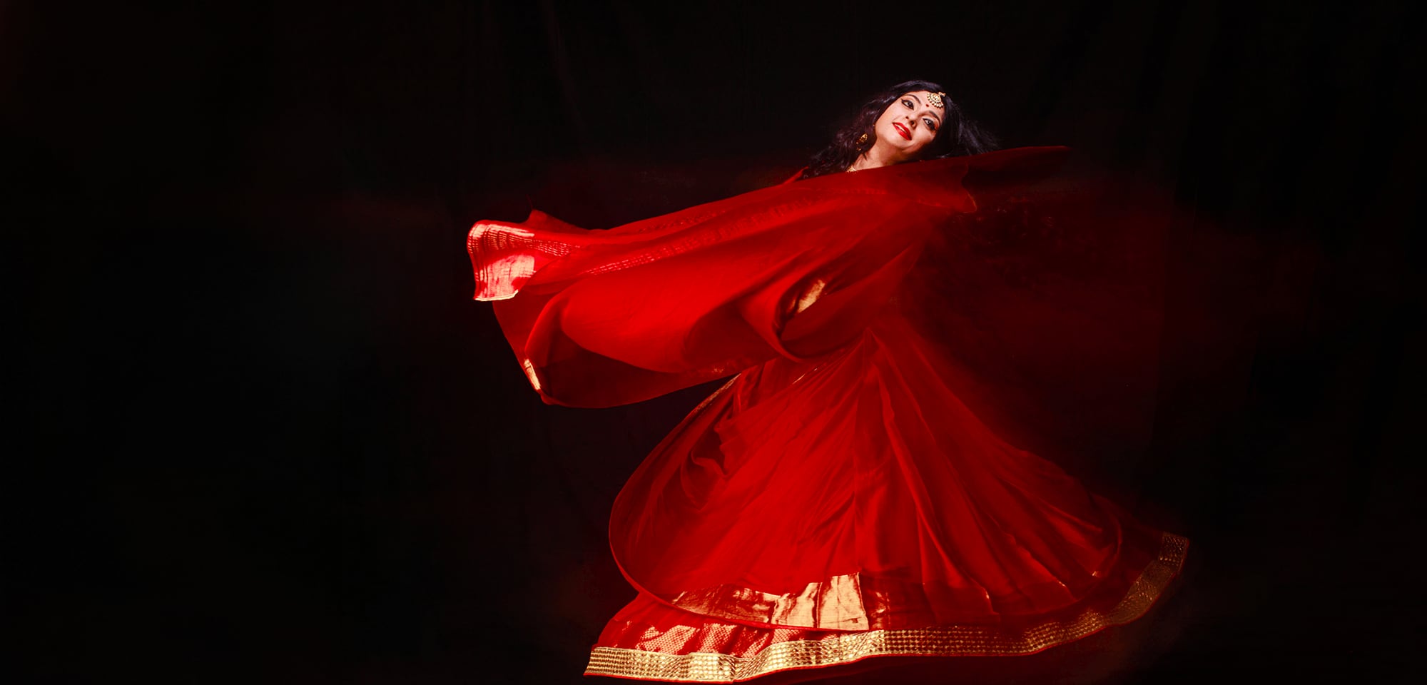 A dancer of Abhinava Dance Company in a swirl of red